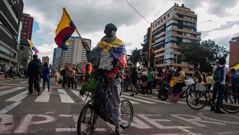 Ein Demonstrant in Bogotá schwenkt eine kolumbianische Flagge bei einer Protestaktion gegen die Gewaltanwendung durch die Polizei. Der kolumbianische Präsident Iván Duque hat nach tagelangen Protesten den Einsatzbefehl für die Sicherheitskräfte…