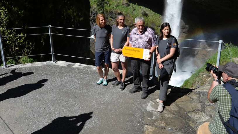 Wegweisend: Zur Eröffnung von Zugang und Aussichtsplattform beim Berglistüber übergeben Anna Kocher (von links), Andrea Gysi und Ulrike Marx Gemeinderat Kaspar Luchsinger einen normgerechten Wegweiser in Wanderweg- respektive Postgelb.