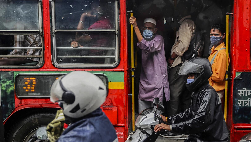 Personen tragen Mund-Nasen-Schutz, als sie in einem voll besetzten Bus fahren. Foto: Rafiq Maqbool/AP/dpa