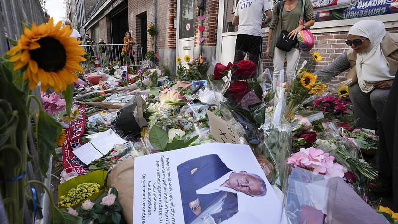 Menschen haben Bilder des Kriminalreporters Peter R. de Vries und Blumen am Tatort in Amsterdam niedergelegt. Der prominente Journalist ist nach dem Mordanschlag seinen schweren Verletzungen erlegen. Foto: Peter Dejong/AP/dpa