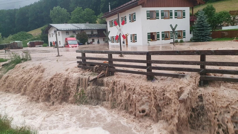 Wasser fließt über einen Platz vor einem Haus. im oberbayerischen Landkreis Berchtesgadener Land. Foto: Kilian Pfeiffer/dpa