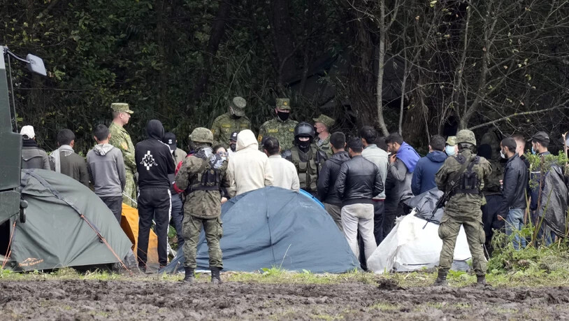 dpatopbilder - ARCHIV - Migranten, die an der Grenze zu Belarus festsitzen, werden von polnischen Beamten umstellt. Polens Grenzschützer haben im September an der Grenze zu Belarus rund 3200 Versuche einer illegalen Einreise registriert. Foto: Czarek…