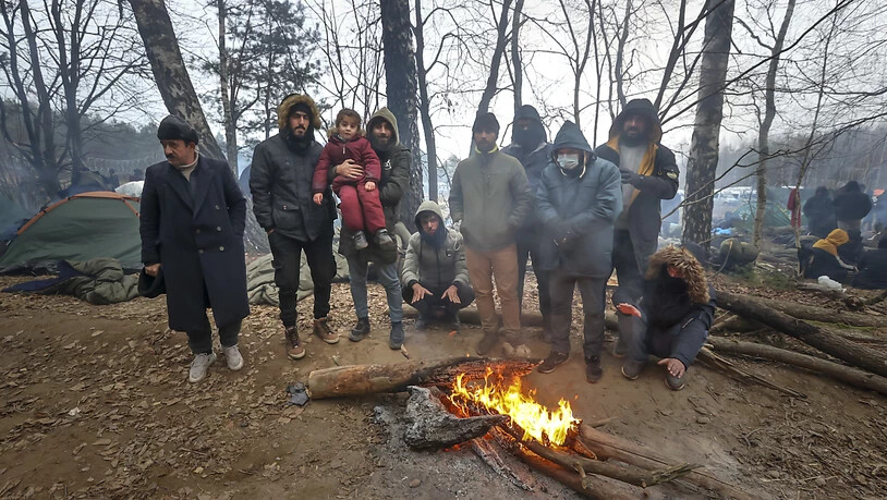 ARCHIV - Migranten versammeln sich an der belarussisch-polnischen Grenze an einem Feuer, um sich zu wärmen. (Archivbild) Foto: Ramil Nasibulin/BelTA/AP/dpa