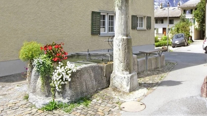 So sieht der Fridlibrunnen im Oberdorf heute aus: Der Zeuge einstiger Tagwen-Fronarbeit ist nun im Ruhestand und ziert als schmucke Dekoration die Dorfstrasse mit Ausblick auf den Ennendaner Hausberg Schilt.