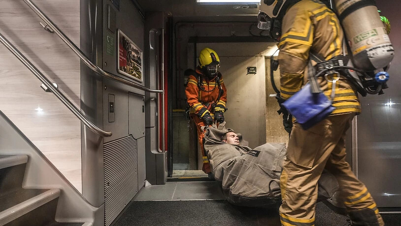 Helfer tragen einen verletzten Figuranten aus einem Doppelstockzug im Rahmen der Rettungsübung im Bözbergtunnel.