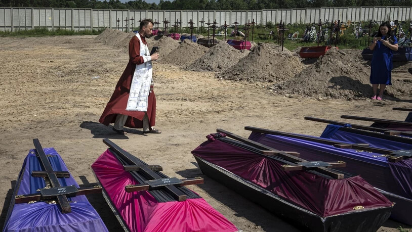 Andrii, ein orthodoxer Priester, segnet die Särge nicht identifizierter Zivilisten, die in einem Massengrab in Butscha gefunden wurden. Foto: Evgeniy Maloletka/AP/dpa