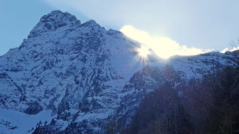 Naturspektakel im November: Die Sonne scheint bei schönem Wetter durch das Mürtschenloch auf das Dorf Mühlehorn.