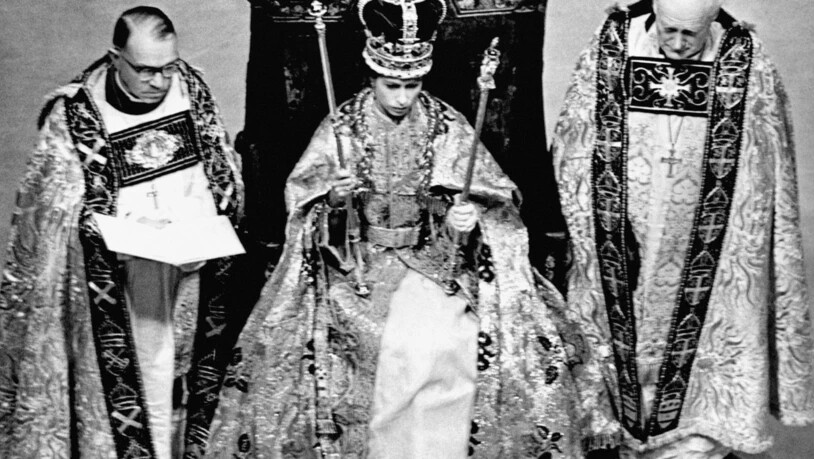 Königin Elisabeth II. (M) trägt nach ihrer Krönung in der Westminster Abbey die Edwardskrone und trägt das Zepter und den Stab. Foto: -/PA Wire/dpa