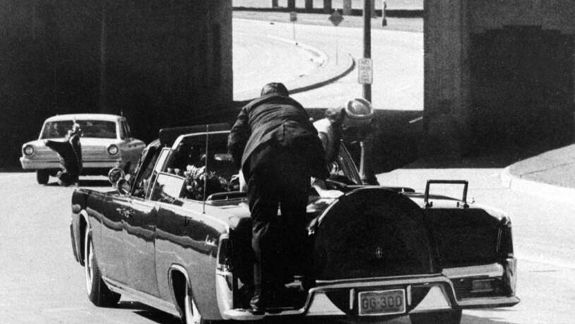 First Lady Jacqueline Kennedy lehnt sich über den getroffenen Präsidenten, während der Secret-Service-Agent auf den Auto-Rücksitz aufspringt, nachdem der Präsident in Dallas erschossen wurde.