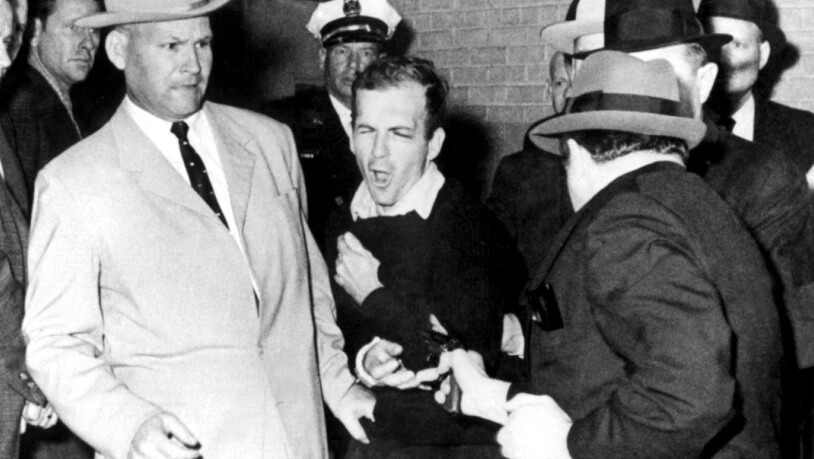 Der mutmassliche Attentäter Lee Harvey Oswald (Mitte) wurde ein paar Stunden nach den tödlichen Schüssen verhaftet. Während der Überführung in ein anderes Gefängnis wurde er von Jack Ruby (Rechts) erschossen. Das Attentat auf Kennedy wurde bis heute…