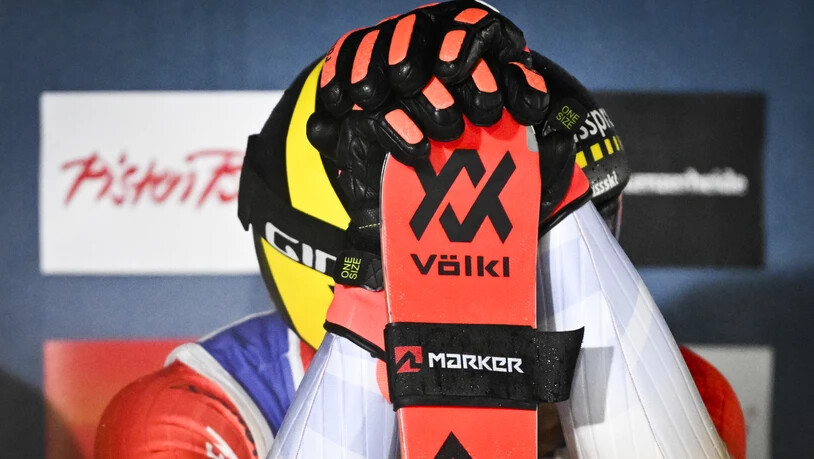 Alex Fiva vergräbt sein Gesicht hinter Ski und Armen