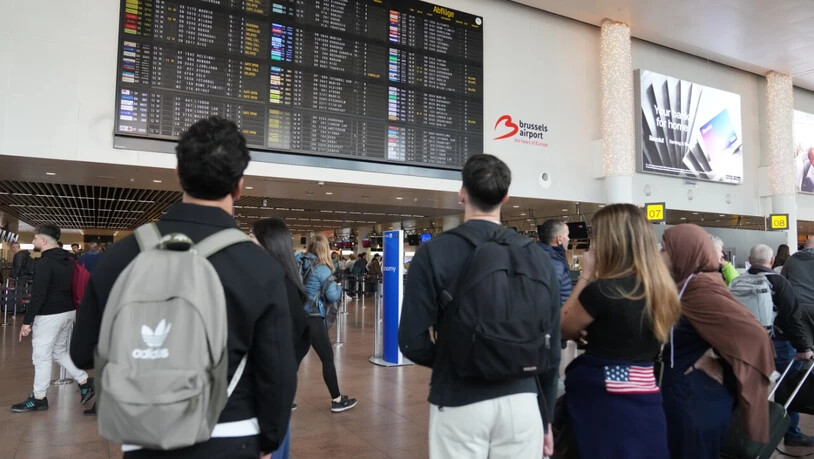 Passagiere schauen auf eine Abflugtafel, nachdem mehrere Flüge gestrichen wurden. Foto: Virginia Mayo/AP/dpa