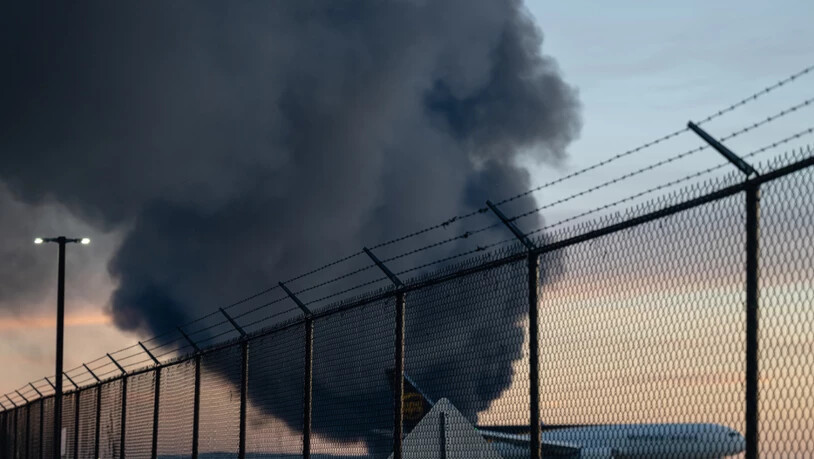 Eine UPS Boeing 737 ist geparkt, während eine Rauchwolke vom Absturz enes UPS-Frachtflugzeugs in der Nähe auf dem Louisville Muhammad Ali International Airport im Hintergrund zu sehen. Foto: Jon Cherry/AP/dpa