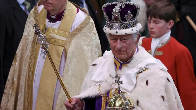 ARCHIV - Großbritanniens König Charles III. verlässt nach der Krönungszeremonie mit der Imperial State Crown, einem Zepter und dem Reichsapfel die Westminster Abbey. Foto: Phil Noble/AP/dpa