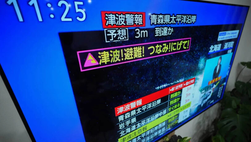 dpatopbilder - Eine Tsunami-Warnung wird auf einem Fernseher in Yokohama, in der Nähe von Tokio, angezeigt. Nach einem starken Erdbeben vor der japanischen Nordküste wurde eine Tsunami-Warnung ausgegeben. Foto: Eugene Hoshiko/AP/dpa