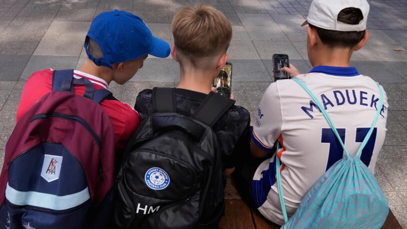 Hugo W., (r-l), Hardy M. und Edan A., alle 11 Jahre alt, benutzen ihre Telefone, während sie vor einer Schule in Sydney sitzen. In Australien dürfen ab sofort Kinder und Jugendliche unter 16 Jahren keine eigenen Konten mehr auf vielen großen Social-Media…