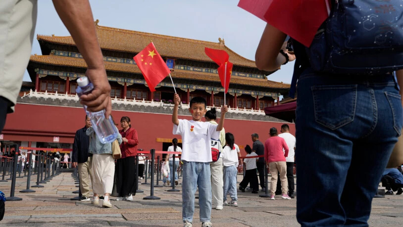 ARCHIV - Ein Kind posiert für Fotos mit chinesischen Nationalflaggen vor der Verbotenen Stadt während des Nationalfeiertags. Foto: Ng Han Guan/AP/dpa