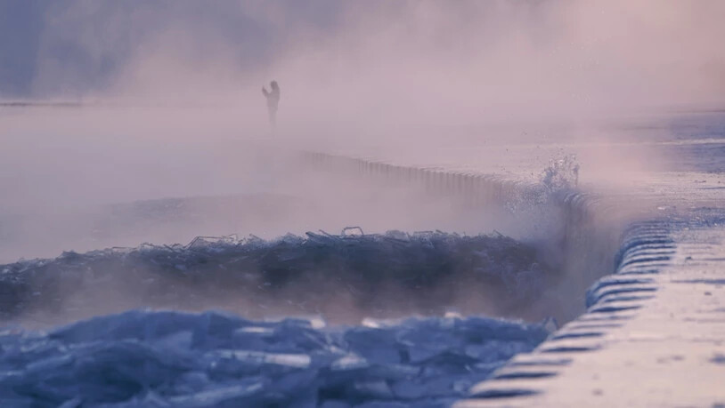Eine Person spaziert über einen mit Eis bedeckten Strand am Ufer des Michigansees. Foto: Kiichiro Sato/AP/dpa
