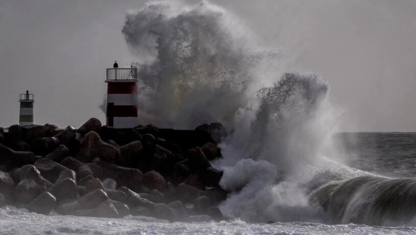 ARCHIV - Große Wellen krachen 2024 gegen einen Leuchtturm bei Nazaré an der Küste Portugals. Foto: Michael Probst/AP/dpa