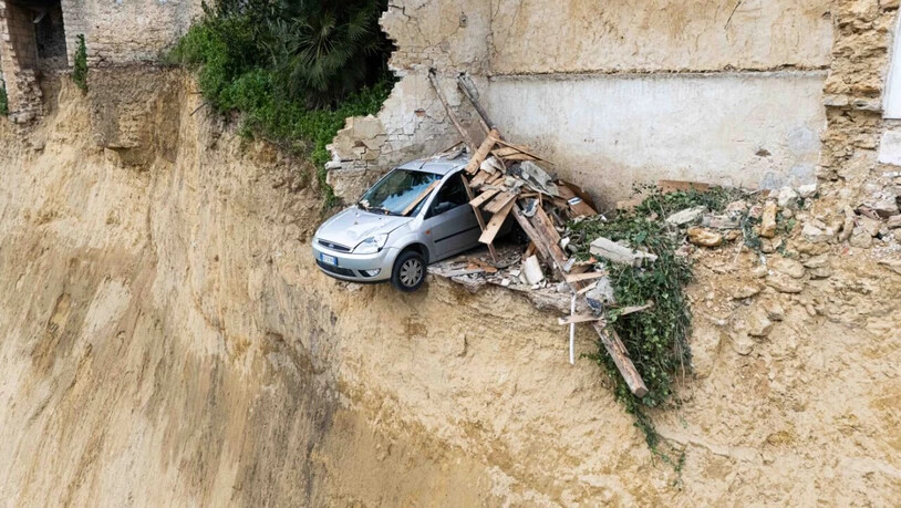 dpatopbilder - In dem Dorf Niscemi ist ein Auto vor einem durch einen Erdrutsch entstandenen Abgrund zu sehen. Nach schweren Unwettern auf Sizilien hat sich in einer Stadt ein massiver Erdrutsch gebildet. Foto: Andrea Petrelli/IPA via ZUMA Press/dpa