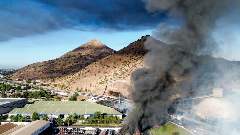 Rauch steigt in den Himmel, nachdem ein mit Flüssiggas beladener Tanklaster in einem Industriegebiet nahe Santiago de Chile umkippte und explodierte. Foto: Hans Scott/Agencia Uno/dpa