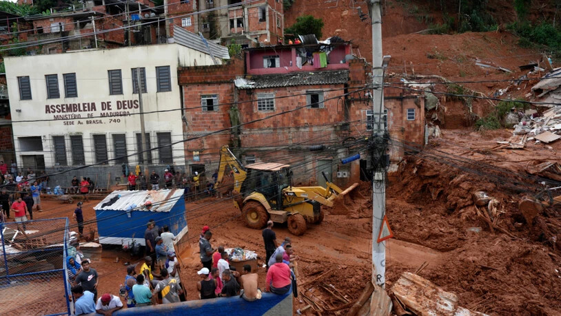 Feuerwehrleute und Mitarbeiter des Zivilschutzes helfen im brasilianischen Bundesstaat Minas Gerais an der Stelle, an der Häuser aufgrund von heftigen Regenfällen und Überschwemmungen in Juiz de Fora eingestürzt sind. Foto: Silvia Izquierdo/AP/dpa