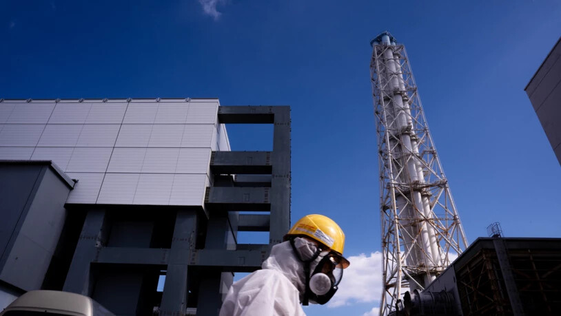 Ein Arbeiter geht am Reaktorblock 4 des von der Tokyo Electric Power Company (TEPCO) betriebenen Kernkraftwerks Fukushima Daiichi in Okuma, Präfektur Fukushima, vorbei. Foto: Louise Delmotte/AP/dpa