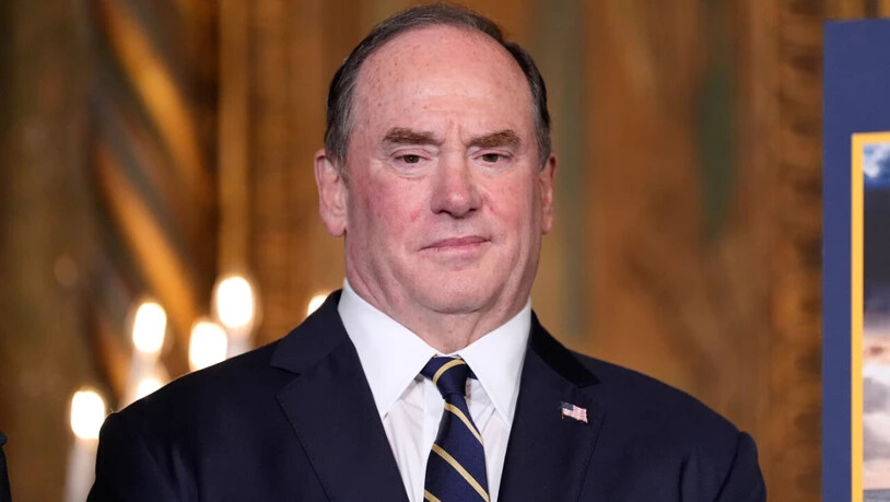 ARCHIV - US-Marineminister John Phelan hört zu, während US-Präsident  Trump in seinem Club Mar-a-Lago spricht. Foto: Alex Brandon/AP/dpa