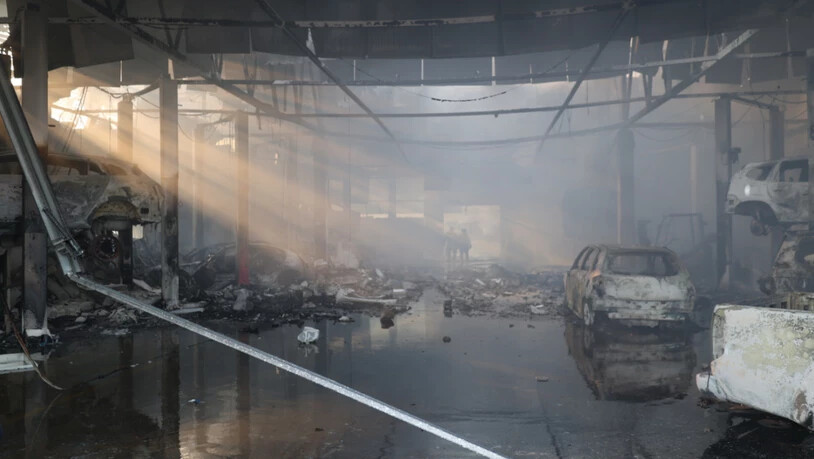 dpatopbilder - HANDOUT - Polizisten gehen durch eine Autowerkstatt in Saporischschja, die durch einen russischen Angriff zerstört wurde. Foto: Ukraine National Police/AP/dpa - ACHTUNG: Nur zur redaktionellen Verwendung und nur mit vollständiger Nennung…