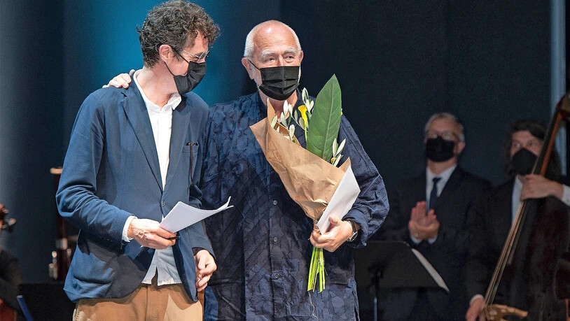 Preisträger hinter der  Maske:  Peter Zumthor (rechts) bedankt sich für Ehre, Blumen und die Laudatio von Men Duri Arquint.