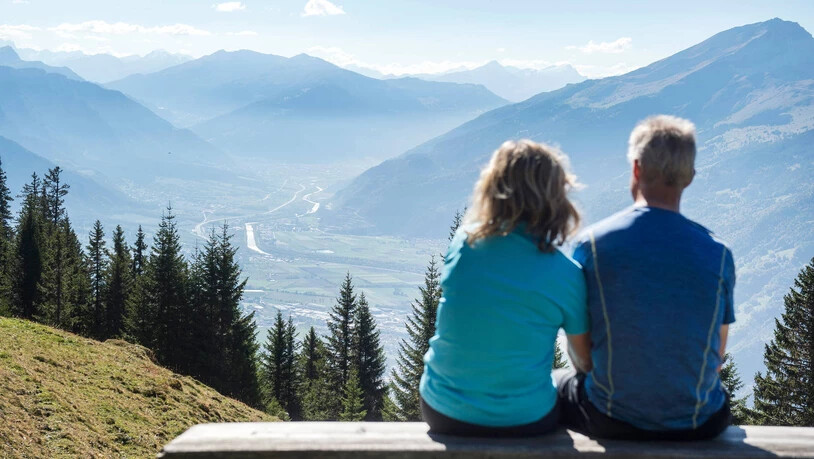 Eine Frau und ein Mann geniessen die Aussicht vom Malanser Älpli auf das Bündner Rheintal. 