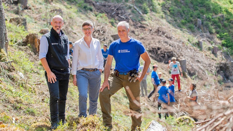 Projekt GKB Sommerjob: Kantonsförster und Leiter des Amts für Wald und Naturgefahren Urban Maissen, die neu gewählte Regierungsrätin und Gemeindepräsidentin von Ilanz/Glion Carmelia Maissen und Geschäftsführer vom Bergwaldprojekt Martin Kreiliger (von links) sind ebenfalls anwesend im Wald oberhalb von Siat. 

