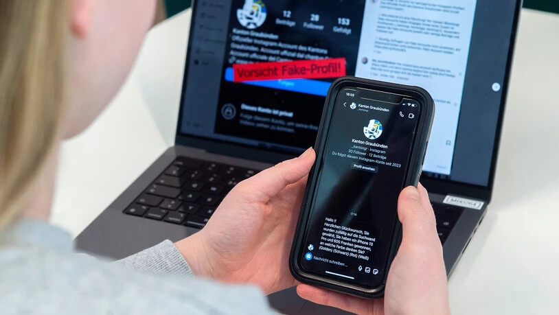 Achtung vor Betrugsmaschen: Ein Fake-Profil des Kantons Graubünden versendet Nachrichten, wonach man ein iPhone gewonnen habe (im Bild). Auf dem Laptop im Hintergrund ist der Warnhinweis der offiziellen Instagram-Seite des «Kanton Graubünden» zu sehen.