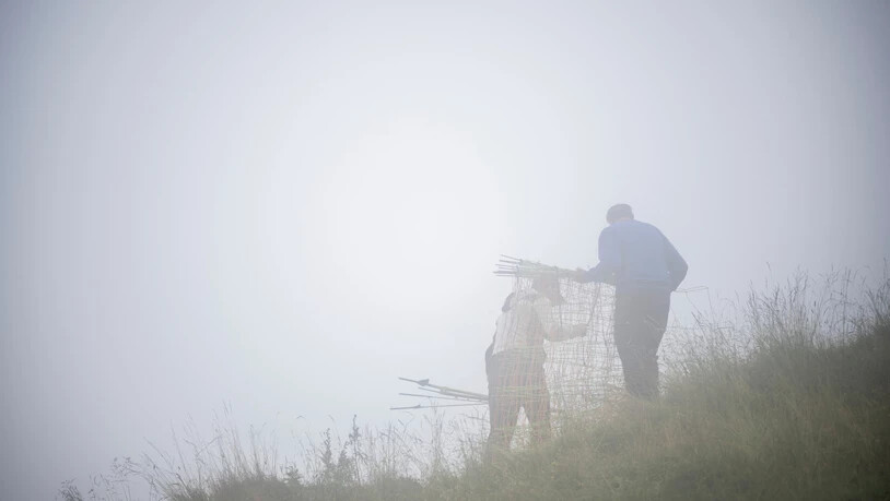 Draussen bei jeder Witterung: Ein Hirt bricht der mit Unterstützung seines Alpmeisters den Zaun einer Alpweide ab.
