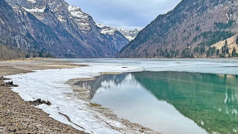Die umliegenden Berge spiegeln sich im See.