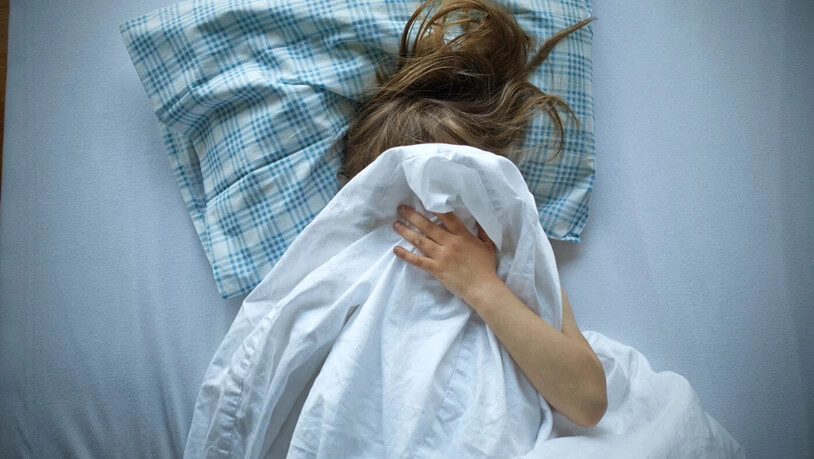 Missbrauch geschieht im nahen Umfeld: Ein Mädchen sucht Schutz und versteckt auf diesem gestellten Bild sein Gesicht unter der Decke ihres Bettes.