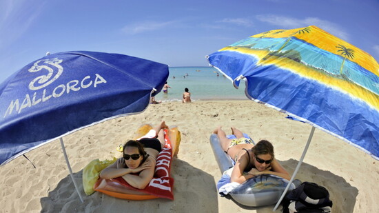 Feriengäste liegen am Strand in Mallorca: Herr und Frau Schweizer zieht es nach dem Wegfall der Corona-Massnahmen wieder vermehrt ins Ausland (Archivbild).