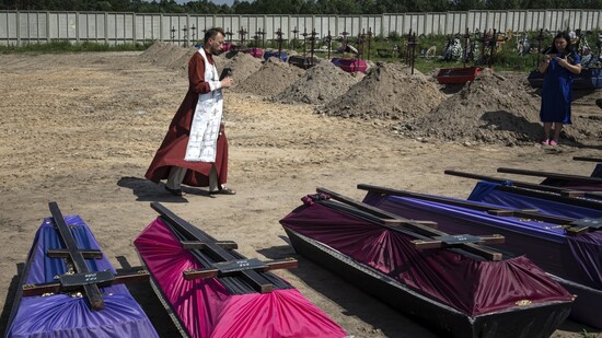 Andrii, ein orthodoxer Priester, segnet die Särge nicht identifizierter Zivilisten, die in einem Massengrab in Butscha gefunden wurden. Foto: Evgeniy Maloletka/AP/dpa
