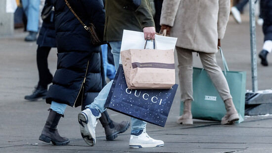 ARCHIV - Menschen gehen mit Einkaufstüten von Gucci durch die Hamburger Innenstadt. Foto: Markus Scholz/dpa