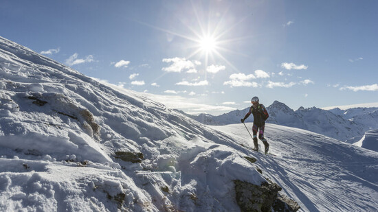 Wechselhaftes Wetter: Ein Athlet geniesst am Sonntagmorgen den Sonnenschein in der Davoser Bergwelt. 