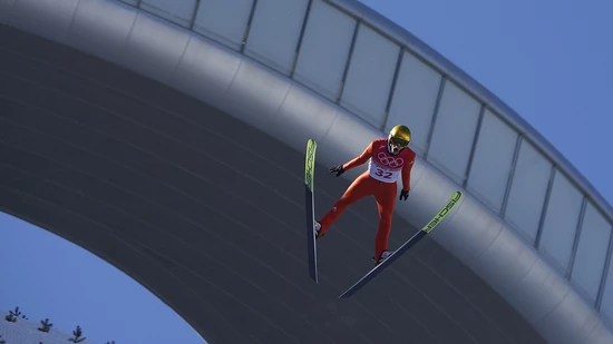 Gregor Deschwanden schwebt runter in den Kessel. Obwohl die Flaggen stramm im Wind stehen, kann auf dieser Anlage gesprungen werden.