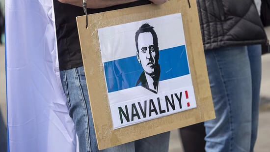 ARCHIV - Ein Mann trägt ein Schild mit dem aufgedruckten Gesicht des verstorbenen Regimegegners Alexej Nawalny. Foto: Thomas Banneyer/dpa