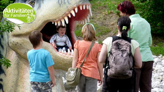 Gefundenes Fressen: Ein kleiner Junge sitzt im Maul eines T-Rex und freut sich.