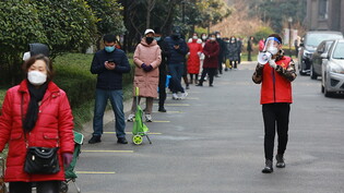 In Xi'an galten einen Monat lang strenge Regeln: Ein freiwilliger Helfer ermahnt Bewohnerinnen und Bewohner via Megafon, den Mindestabstand beim Schlangestehen für Bedarfsartikel einzuhalten. Foto: Uncredited/CHINATOPIX/AP/dpa