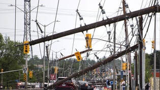 Ein Fahrzeug steht nach einem schweren Sturm auf der Merivale Road zwischen umgestürzten Stromleitungen und Versorgungsmasten. In Kanada sind am Wochenende bei mehreren heftigen Stürmen und Gewittern mindestens fünf Menschen ums Leben gekommen. Foto:…