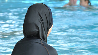 ARCHIV - Eine muslimische Schülerin sitzt in einem Ganzkörperbadeanzug (Burkini) am Rande eines Schwimmbeckens. In Frankreich ist erneut ein Streit um Burkinis ausgebrochen. Foto: Rolf Haid/dpa