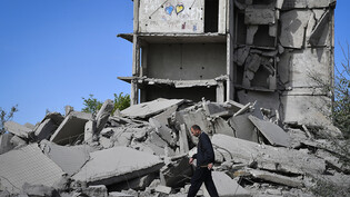 Ein Anwohner geht an einem durch russischen Beschuss zerstörten Haus vorbei. Foto: Andriy Andriyenko/AP/dpa