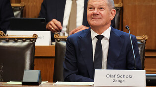 Bundeskanzler Olaf Scholz sitzt auf seinem Platz auf der Senatsbank mit einem Plastikschild mit dem Text "Olaf Scholz Zeuge" vor Beginn einer Sitzung des Parlamentarischen Untersuchungsausschusses "Cum-Ex" im Plenarsaal der Hamburgischen Bürgerschaft im…