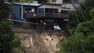 Ein durch Hochwasser verursachter Erdrutsch untergräbt ein Haus. Foto: Hadyen Woodward/New Zealand Herald/AP/dpa