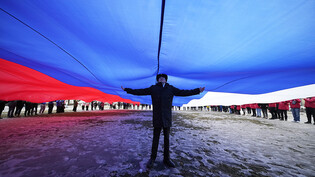 Ein Marinekadett steht unter einer riesigen russischen Flagge während einer Feier zum neunten Jahrestag der Annexion der Krim durch Russland. Foto: Dmitri Lovetsky/AP